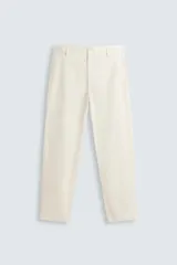 Pantalón chino de algodón color crema, corte regular fit, con cierre frontal de cremallera y botón, bolsillos delanteros y bolsillos traseros de vivo con botón.