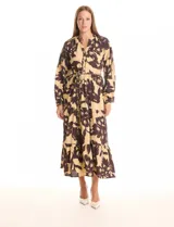 Vestido maxi de crepe estampado con flores grandes en tonos beige y marrón oscuro. Presenta escote en V con botones, mangas largas anchas con botón en los puños, y cintura con pasadores y cordón de ajuste.