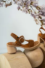 Sandalias de cuero color marrón con tiras anchas y hebilla plateada. Taco de madera.
