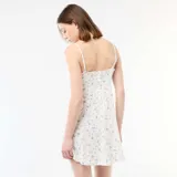 Vestido corto blanco con estampado floreado azul, tirantes finos, escote en V con detalle de encaje y falda acampanada.