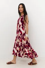Vestido midi sin mangas, con escote redondo, de corte recto y ligero vuelo en el ruedo. Presenta un estampado animal print abstracto en tonos rojo, bordó y beige.