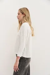 Remera azul de algodón peruano con textura jaspeada, de moldería holgada y buena caída, con mangas largas que se ajustan hacia la muñeca y se ensanchan debajo del brazo.