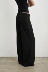 Pantalón palazzo negro de tiro alto con cintura ancha plegable, confeccionado en tela de punto fruncida y corte holgado.