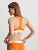 Bralette deportivo naranja de algodón modal con espalda cruzada y banda elástica blanca con logo de Calvin Klein.