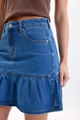 Falda corta de jean color azul medio, de tiro medio con diseño de volado en el ruedo.