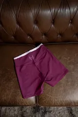 Calza deportiva corta color bordó con tiro alto y costuras planas. Presenta un logo estampado en blanco en la pierna, que consiste en un objeto con alas.
