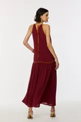 Vestido largo color bordó con escote halter, diseño holgado y detalles de ribetes en contraste.