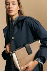 Cartera estructurada de símil cuero con diseño de bloques de color: principal en color camel, laterales en blanco y solapa frontal en negro. Posee correa larga regulable y desmontable.