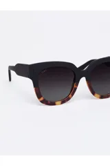 Lentes de sol Tiwi modelo Kerr, con montura gruesa de acetato color negro en la parte superior y estampado carey en la parte inferior.