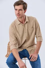 Camisa de lino de manga larga en color beige, con cuello camisero, cierre frontal de botones y un bolsillo ojal en el pecho.