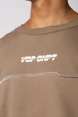 Buzo oversize de corte boxy, confeccionado en algodón rústico de alto gramaje en color beige. Presenta cuello redondo con borde crudo, mangas largas y una estampa frontal con el texto VCP delimitado por líneas horizontales blancas.