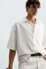 Camisa de corte relajado confeccionada en tejido mezcla de lyocell, con cuello solapa, manga corta y cierre frontal con botonadura oculta.