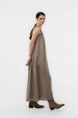 Vestido largo de lino color tostado, con silueta amplia, escote cuadrado con frunces elastizados y breteles anchos con detalles de volados.