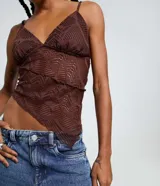 Top de encaje marrón oscuro con patrón geométrico calado, escote en V y breteles finos ajustables. El ruedo es asimétrico y tiene forro solo en la zona del busto.
