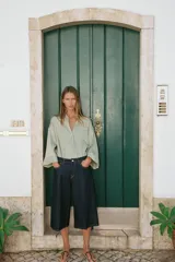 Camisa de corte oversize color marrón, con cuello solapa, mangas anchas por debajo del codo y bolsillo delantero de plastrón. Cierre frontal con botones.