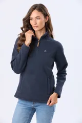 Buzo de polar color crema con cuello alto y cierre frontal parcial. Presenta detalles en cuero en el tirador del cierre y un pequeño bordado en el pecho y en la manga.