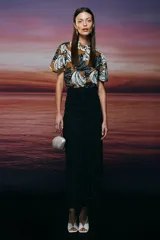 Falda midi de jeans negro, corte tubo con abertura diagonal frontal y botón metálico con forma de boca.