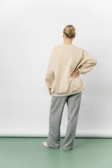 Buzo oversize de algodón frizado color beige, con cuello redondo, puños y cintura tejidos. Presenta un bordado tono sobre tono de Garfield en el frente.