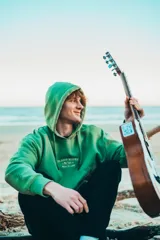 Hoodie verde con estampado en la espalda que dice "GlassyWaves Surf Company Ride Your Own Wave".