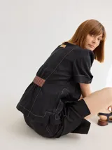 Chaqueta de lino color negro con costuras a contratono, mangas cortas con dobladillo y detalle de franja texturizada en la cintura. Presenta cuello camisero y etiqueta de cuero en la espalda.