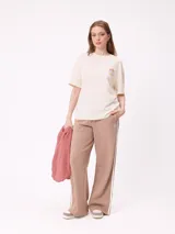 Remera de algodón con corte holgado, color crema, con estampado gráfico en la espalda que incluye un sol, montañas y mariposas con la frase Realities Rusty Collide.