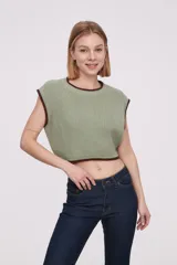 Chaleco corto de punto color verde claro con ribetes marrones en cuello, sisas y ruedo.