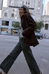 Cazadora de ante color marrón oscuro, con cuello solapa, manga larga y cierre frontal de botones. Incluye dos bolsillos delanteros de plastrón con solapa.