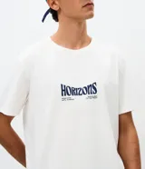 Remera masculina blanca de manga corta y cuello redondo, con estampa en la espalda de una tabla de surf, olas y la inscripción "Horizons".