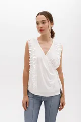 Musculosa cruzada de color beige, con escote en V y volados decorativos en los hombros y el frente.