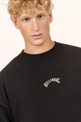 Buzo Billabong Arch Over Crew de color negro, con cuello redondo y diseño de mangas caídas. Presenta un pequeño bordado en hilo blanco en el centro del pecho con el nombre de la marca en tipografía arqueada.