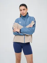 Campera cortaventos Umbro de diseño colorblock en tonos celeste, beige y azul marino, con cuello alto, cierre frontal y bolsillos laterales.