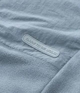 Buzo de fleece color verde agua con capucha ajustable, cierre frontal completo y bolsillo con cierre en el pecho. Presenta un diseño funcional con recortes en tejido plano y calce regular.