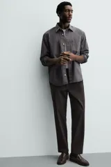 Pantalón de corte regular fit, color negro, confeccionado en tejido elástico. Presenta cintura elástica, cierre frontal con cremallera y botón, bolsillos laterales y bolsillos traseros de vivo.