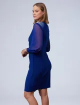 Vestido de fiesta azul eléctrico, marca RM Richards, confeccionado en seda fría. Presenta escote en V cruzado, drapeado lateral, mangas largas de gasa y apliques de strass en los hombros.