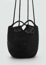 Bolso de mano tipo cesta de tamaño pequeño, confeccionado en material trenzado de color negro. Cuenta con doble asa corta para llevar en la mano y una correa larga fina para usar al hombro o cruzado.