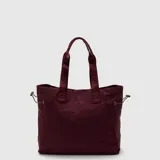 Tote bag color negro de diseño minimalista, con correas de hombro reforzadas con el logo de la marca y elásticos laterales ajustables.