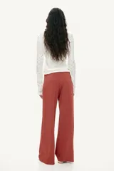 Pantalón de punto pesado color terracota, de corte amplio y pernera recta. Cuenta con cintura elástica revestida y pliegues frontales.