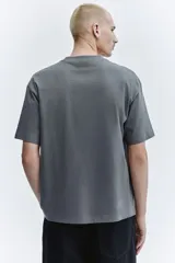 Remera de algodón de peso medio color gris, con cuello redondo ribeteado, hombros caídos, mangas cortas y corte relajado.