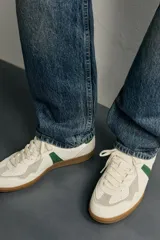 Zapatillas de estilo retro para hombre, color blanco off-white con detalles en verde oscuro y suela de goma marrón estilo gum. Presenta cordones al tono, refuerzos en gamuza en la puntera y talón, y bandas laterales verdes en contraste.