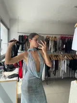 Vestido largo de fiesta con estampado abstracto en tonos celeste y dorado. Tiene escote halter pronunciado y espalda descubierta.