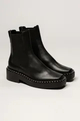 Botas Chelsea negras de cuero, con plataforma track y detalle de tachas plateadas en la suela.