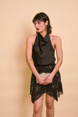 Blusa de satén color negro, sin mangas, con cuello volcado y diseño fluido.