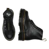 Botas Dr. Martens modelo Sinclair, confeccionadas en cuero Milled Nappa de textura granulada. Presentan una suela Quad con plataforma y cámara de aire, pespuntes amarillos característicos y un cierre frontal extraíble sobre los cordones.