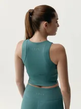 Top deportivo color beige, de cuello redondo con cierre frontal parcial y diseño ajustado.