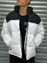 Campera puffer blanca con canesú y cuello alto negros, cierre frontal con cremallera y bolsillos laterales con cierre.