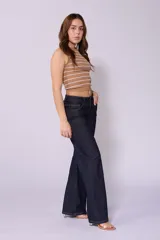 Jean de corte wide leg y tiro bajo, color azul oscuro, con costuras laterales desplazadas hacia el frente y cierre frontal con botón.