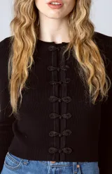 Top negro de tejido de punto acanalado con mangas largas y cierre frontal con botones decorativos.