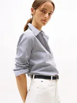 Camisa de popelina a rayas verticales azules y blancas, de corte regular, con cuello inglés y puños con botón. Logo de Tommy Hilfiger bordado en el pecho.