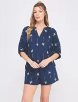 Blusa de rayón y poliéster color azul marino con bordados de palmeras en tono beige, cuello en V, mangas 3/4 holgadas con puño ajustado y diseño holgado de corte asimétrico.