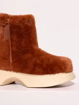 Bota de media caña color marrón, realizada en pelo sintético con detalles en cuero vacuno y suela de eva. El interior está forrado en cuero vacuno.